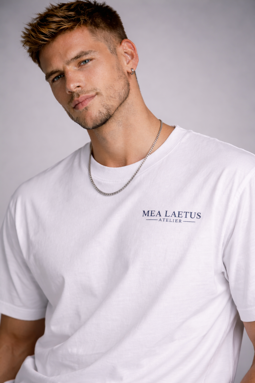 Model trägt weißes T-Shirt mit kleinem schwarzen MEA LAETUS Atelier Brustlogo. Nahaufnahme Foto.