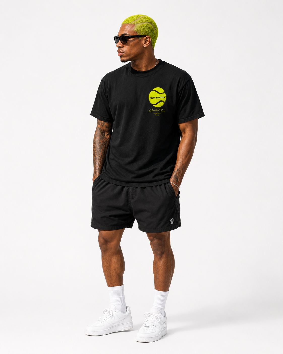 Ganzkörperansicht eines Models im schwarzen Tennis Sports Club Graphic T-Shirt für Herren mit kleinem Neon-Tennisball-Frontprint links.